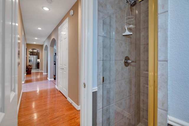 bathroom with a shower stall, baseboards, and wood finished floors