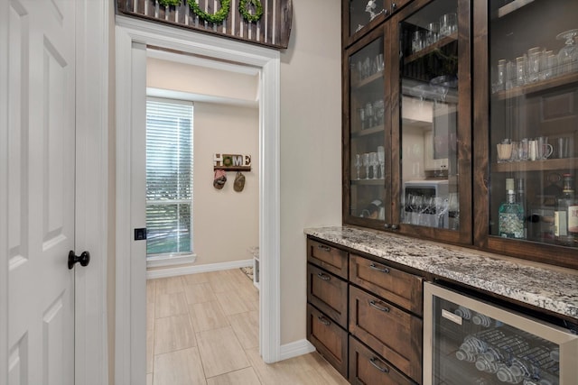 bar with beverage cooler, a bar, and baseboards