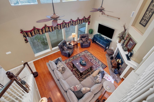 living area featuring a high ceiling, a ceiling fan, and wood finished floors