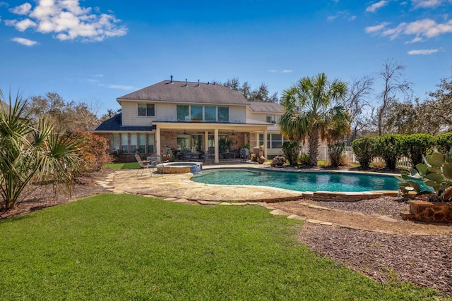 rear view of house with a pool with connected hot tub, a lawn, fence, and a patio