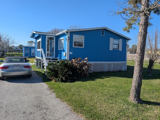 view of front of home with aphalt driveway, a front yard, and fence