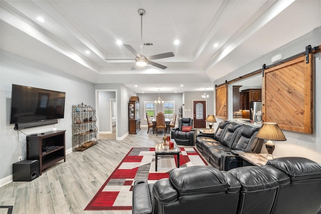 8133 N Fm 565th Rd, Baytown, TX 77523 - living area with a barn door, a tray ceiling, ceiling fan with notable chandelier, and light wood-type flooring