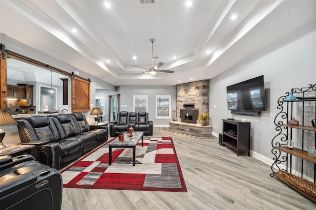 8133 N Fm 565th Rd, Baytown, TX 77523 - living area featuring a barn door, a tray ceiling, a ceiling fan, baseboards, and light wood-style flooring