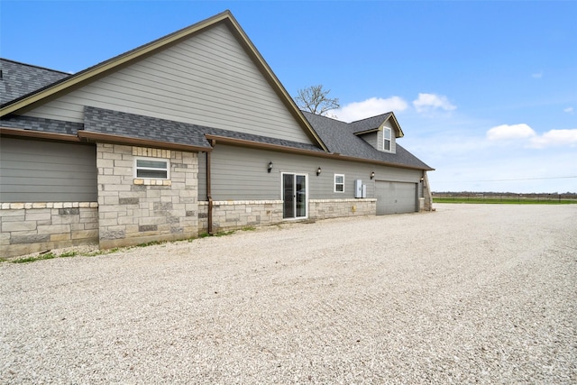 8133 N Fm 565th Rd, Baytown, TX 77523 - back of house with stone siding, driveway, roof with shingles, and a garage