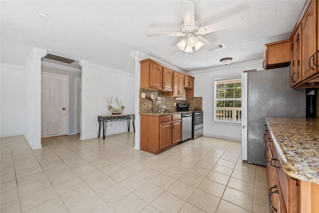 kitchen featuring crown molding, ceiling fan, brown cabinetry, stainless steel appliances, and backsplash
