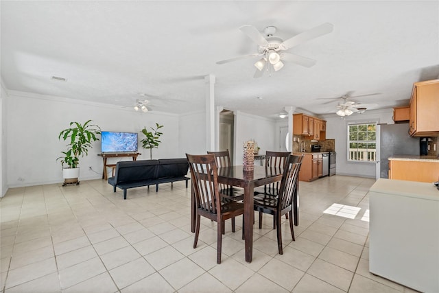 dining room featuring ornamental molding, light tile patterned flooring, baseboards, and a ceiling fan