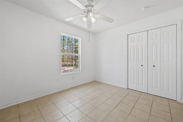 unfurnished bedroom featuring a closet, light tile patterned flooring, ceiling fan, a textured ceiling, and baseboards