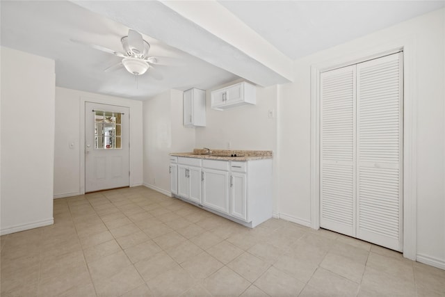 kitchen featuring ceiling fan, light stone countertops, white cabinetry, and baseboards