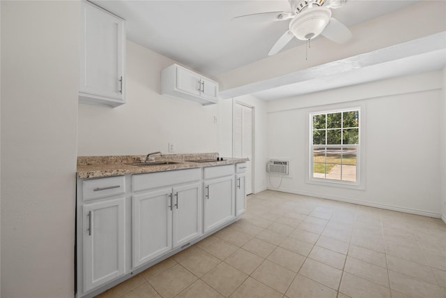 kitchen featuring ceiling fan, a sink, white cabinetry, baseboards, and a wall mounted AC