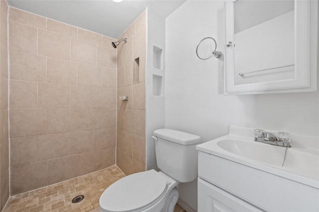 bathroom with tiled shower, vanity, and toilet