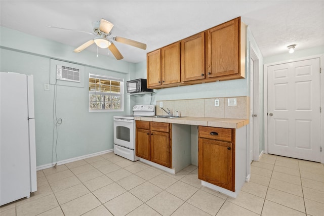 kitchen featuring tile counters, brown cabinetry, a ceiling fan, a sink, and white appliances