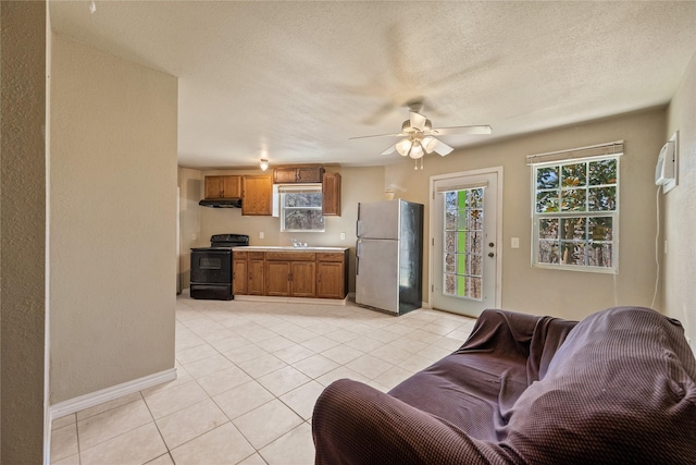 living area with a ceiling fan, a textured ceiling, baseboards, and light tile patterned floors