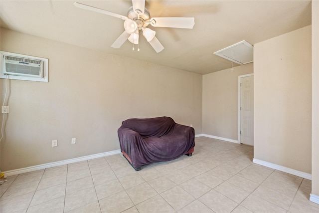 living area featuring light tile patterned flooring, baseboards, attic access, a wall mounted AC, and a ceiling fan