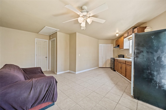 interior space with ceiling fan, black / electric stove, brown cabinetry, light tile patterned floors, and freestanding refrigerator