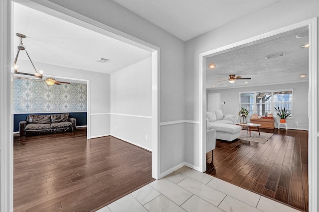 corridor featuring a textured ceiling, baseboards, wood finished floors, and an inviting chandelier