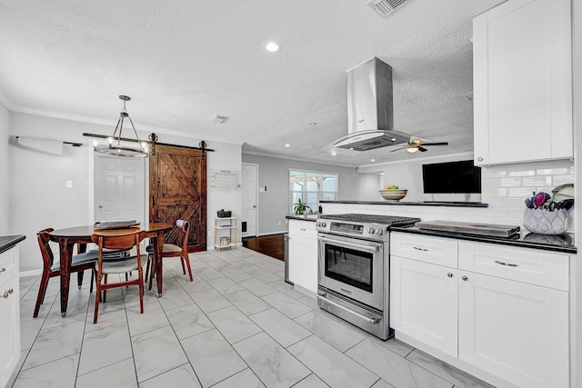 kitchen featuring range hood, crown molding, dark countertops, a barn door, and gas range