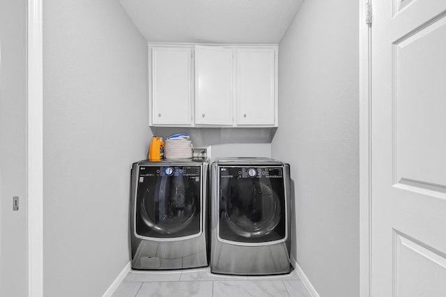 washroom with cabinet space, washer and clothes dryer, and baseboards