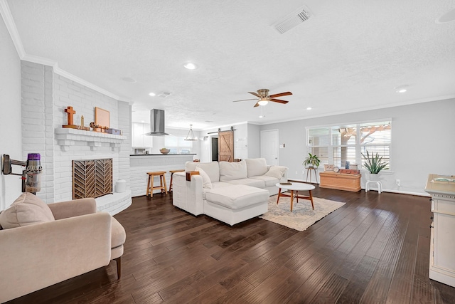 living room featuring dark wood-style floors, a barn door, visible vents, and a textured ceiling