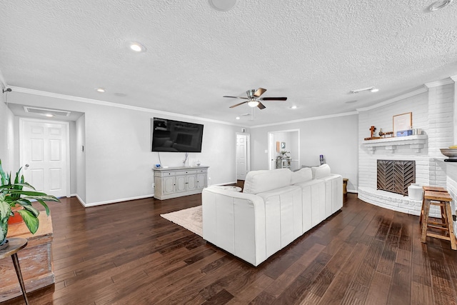 living area with a ceiling fan, ornamental molding, dark wood-style flooring, a textured ceiling, and a fireplace