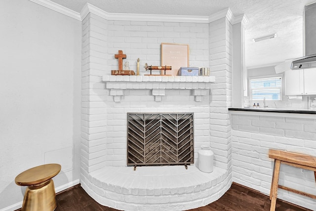 interior details featuring a textured ceiling, a brick fireplace, and wood finished floors