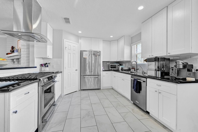 kitchen with a sink, visible vents, ventilation hood, appliances with stainless steel finishes, and dark countertops