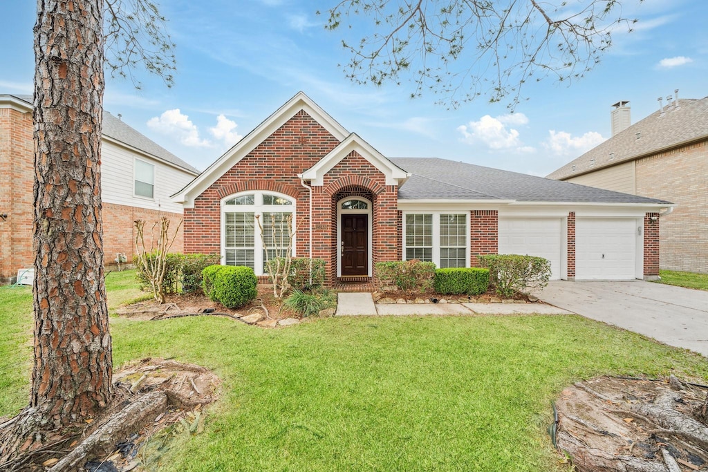 2348 Autumn Mist Ln, League City, TX 77573 - view of front facade featuring brick siding, a shingled roof, a front yard, a garage, and driveway