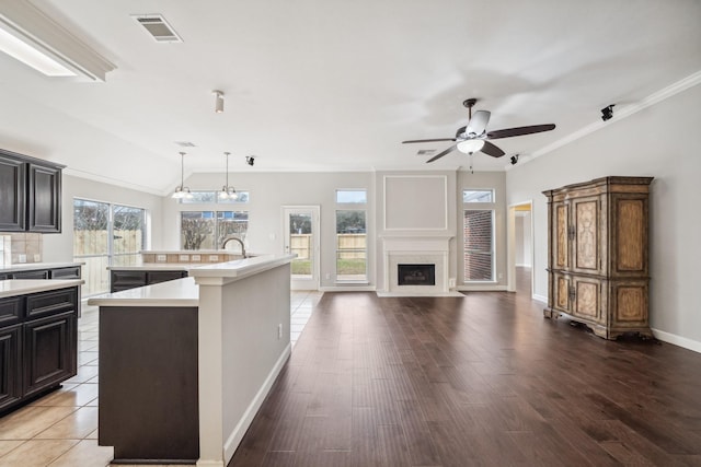 kitchen with a large island, visible vents, light countertops, and a fireplace with flush hearth