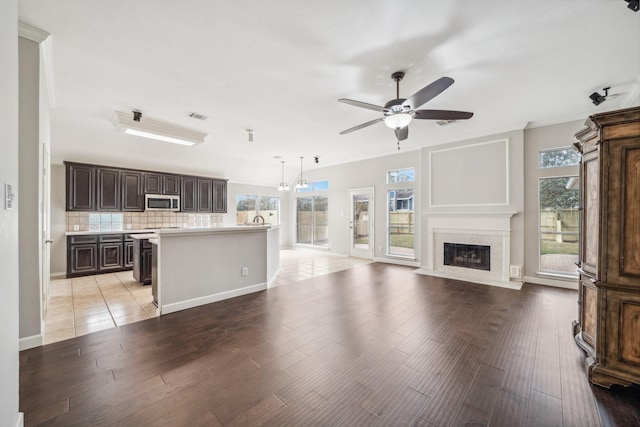 unfurnished living room featuring baseboards, visible vents, a ceiling fan, a premium fireplace, and light wood-type flooring