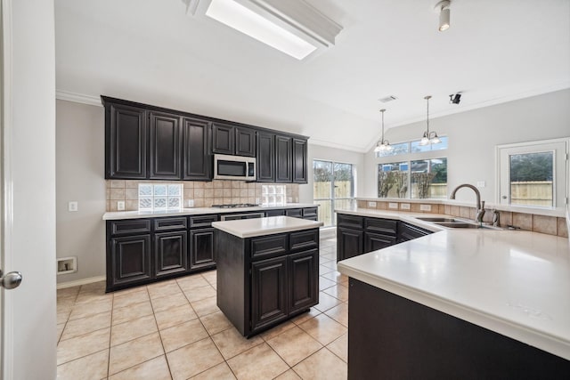 kitchen with a large island, decorative backsplash, appliances with stainless steel finishes, a sink, and dark cabinets