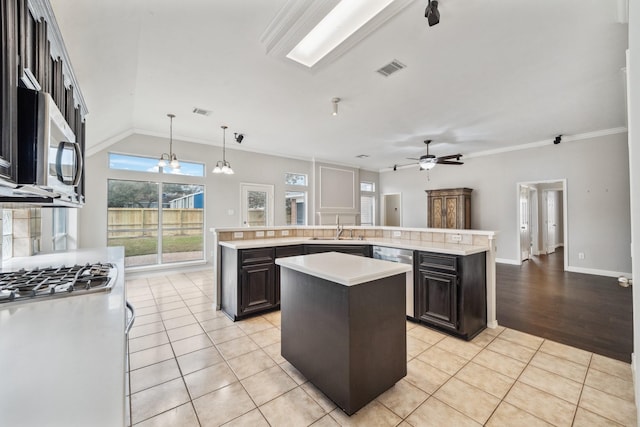 kitchen with light tile patterned floors, a large island, stainless steel appliances, light countertops, and a sink