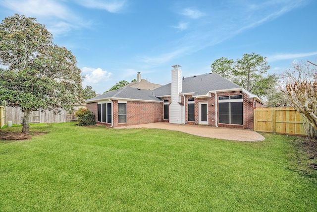 rear view of house featuring brick siding, a yard, a chimney, a patio area, and a fenced backyard