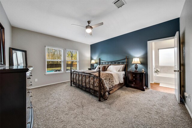 carpeted bedroom with a ceiling fan, visible vents, connected bathroom, and baseboards