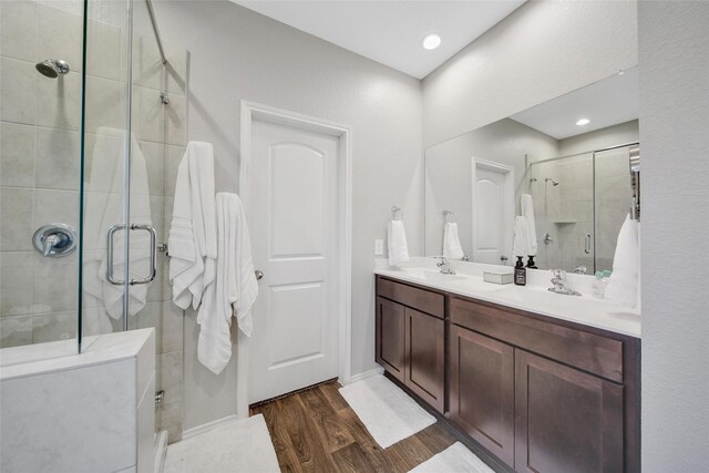 bathroom featuring double vanity, a sink, a shower stall, and wood finished floors