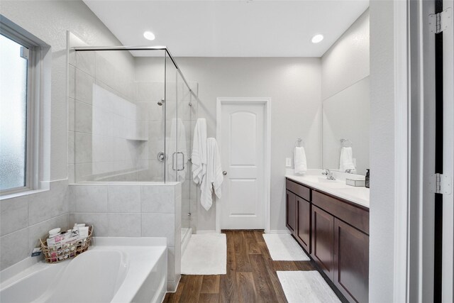 bathroom with a garden tub, recessed lighting, a stall shower, vanity, and wood finished floors