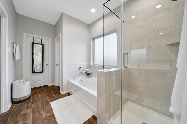 full bath with recessed lighting, wood finished floors, baseboards, a shower stall, and a bath