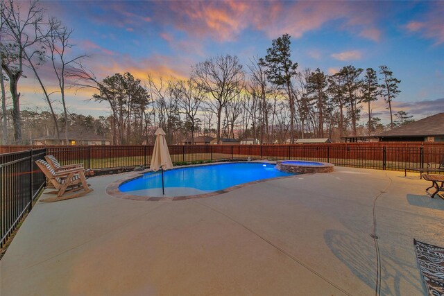 pool at dusk featuring a patio, a fenced backyard, and a pool with connected hot tub