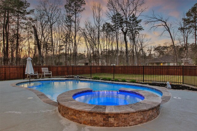 pool at dusk featuring a fenced backyard, a patio, a fenced in pool, and an in ground hot tub