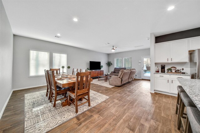 dining room with light wood finished floors, a wealth of natural light, and baseboards