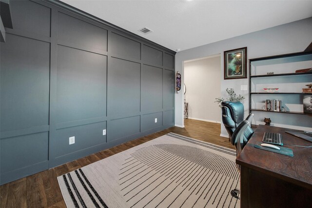 office with dark wood-type flooring, visible vents, and a decorative wall