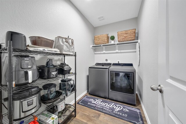 laundry area with laundry area, baseboards, washer and dryer, and wood finished floors