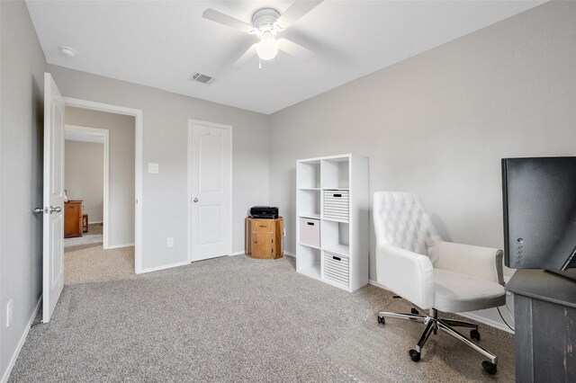 carpeted home office with a ceiling fan, visible vents, and baseboards