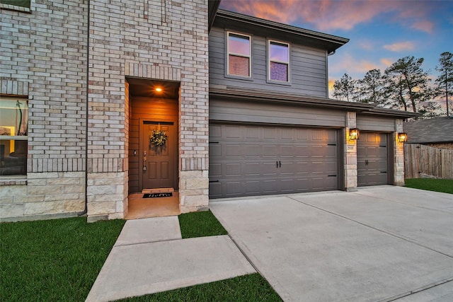 view of front of home with driveway, brick siding, and fence