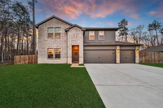 view of front of home with driveway, an attached garage, fence, a front lawn, and brick siding