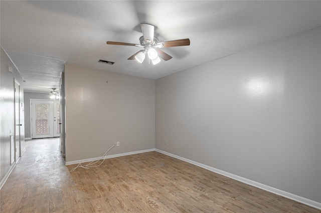 spare room with visible vents, ceiling fan, light wood-style flooring, and baseboards