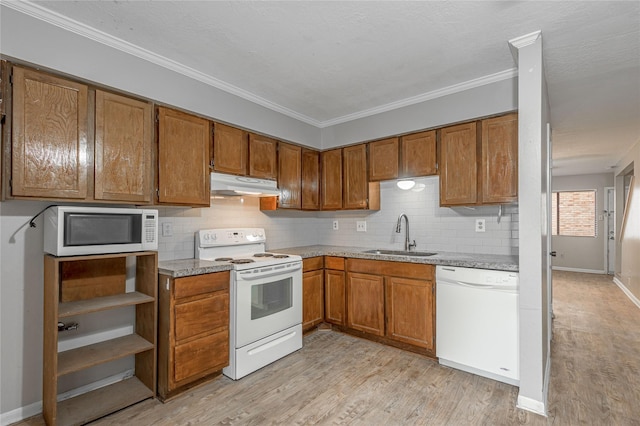 kitchen featuring under cabinet range hood, white appliances, a sink, light wood-type flooring, and brown cabinets