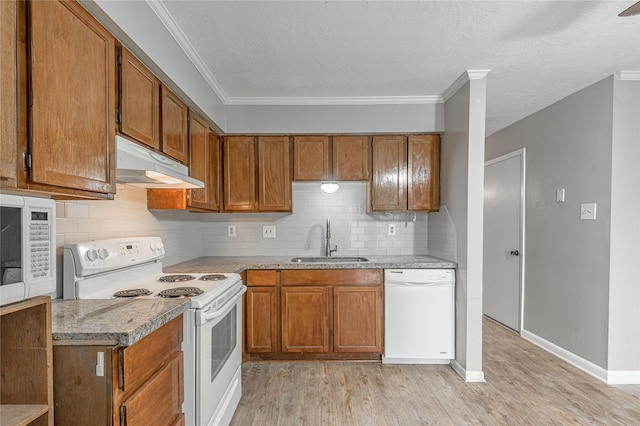 kitchen featuring under cabinet range hood, white appliances, a sink, and brown cabinetry