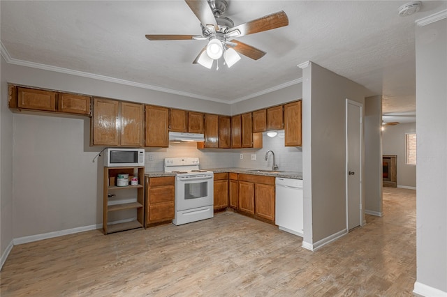 kitchen featuring brown cabinets, white appliances, a sink, and under cabinet range hood