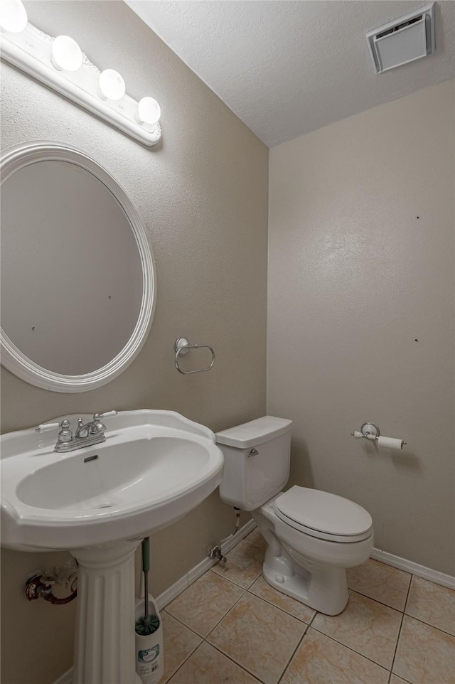 bathroom with baseboards, visible vents, toilet, and tile patterned floors