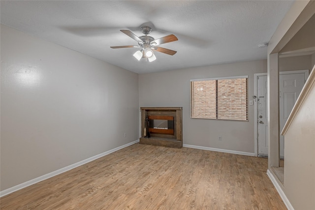 unfurnished living room with light wood finished floors, ceiling fan, and baseboards