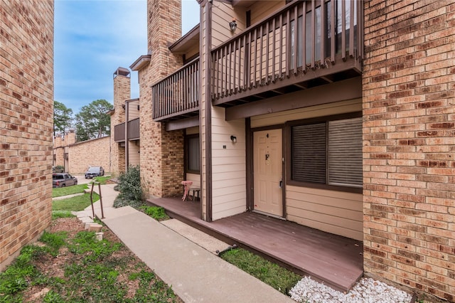 doorway to property with brick siding and a balcony